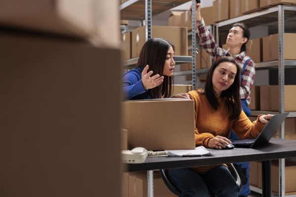 Storehouse employees checking customer delivery satisfaction on laptop